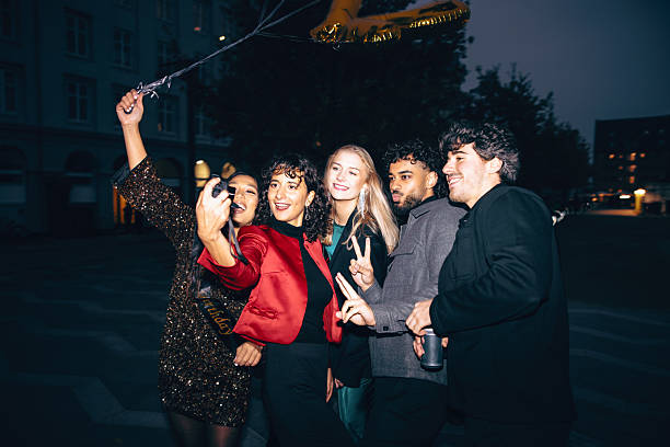A group of friends enjoy a fun night out, holding drinks and celebrating together. The photograph has been done with a film camera, giving it a vintage, dusty look.