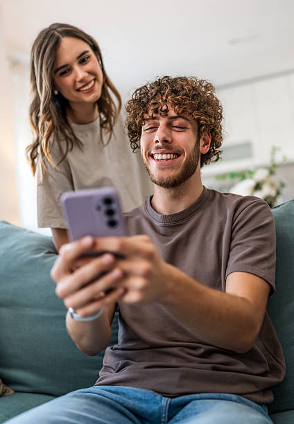 istock Happy young couple laughing using smartphone at home 2239948043