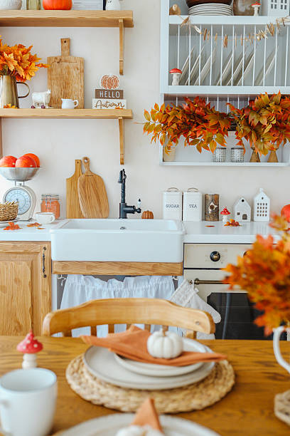 istock Autumn kitchen decor with orange maple leaves, pumpkins, and rustic wood 2239948210