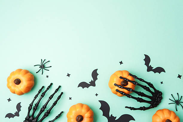 istock Halloween orange pumpkins black skeleton hand bats spiders decorative stars on mint backdrop 2239948389
