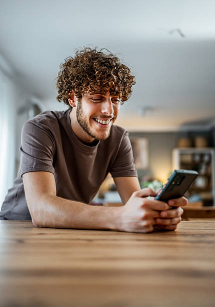 istock Young man smiling while texting on smartphone at home 2239949044
