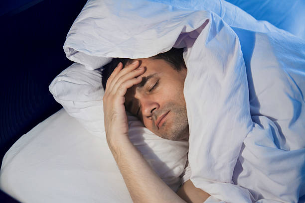 istock Man experiencing discomfort while sleeping in a cozy bed at home during nighttime 2239950090