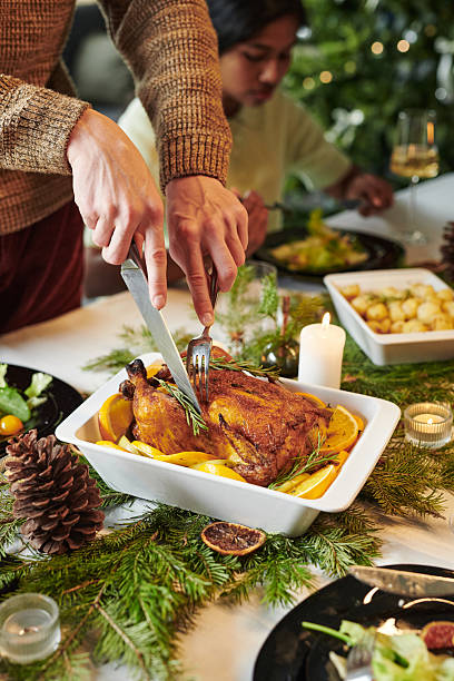 Young Adult Woman Carving Roast Chicken during Christmas Dinner Gathering