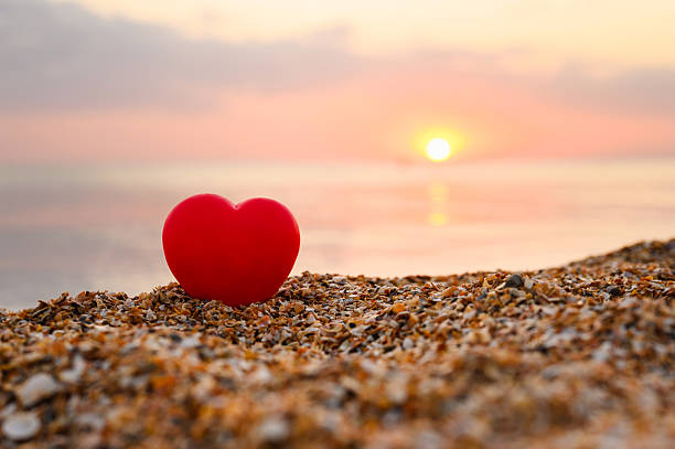 Red heart on the seashore. Romantic sunset on the seashore.