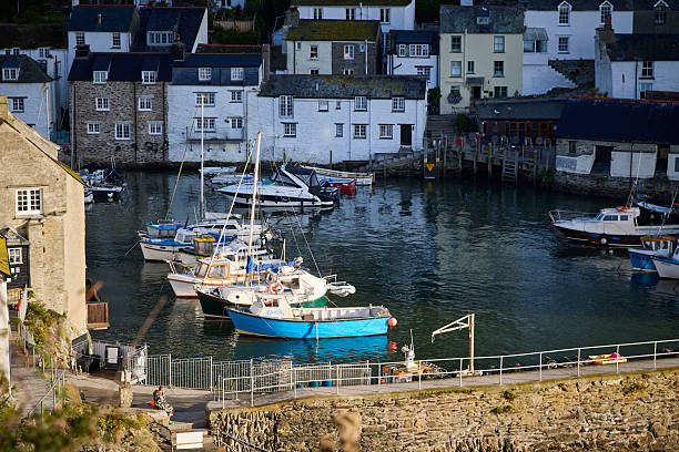 Polperro village and harbour cornwall, england, UK at high tide during a sunny day. Polperro on the south east coast of cornwall still has a busy working harbour mainly used by local fishermen and tourist boat trips, the quaint cottages are typical of cornish villages.