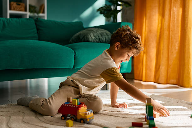 istock Young boy playing with building blocks on living room floor 2239951692