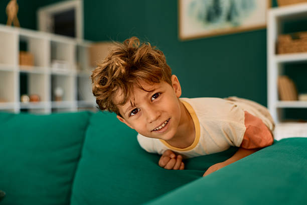 istock Little boy peeking over sofa playing at home 2239952435