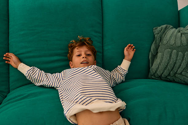 istock Happy young boy relaxing on comfortable teal sofa indoors 2239952554