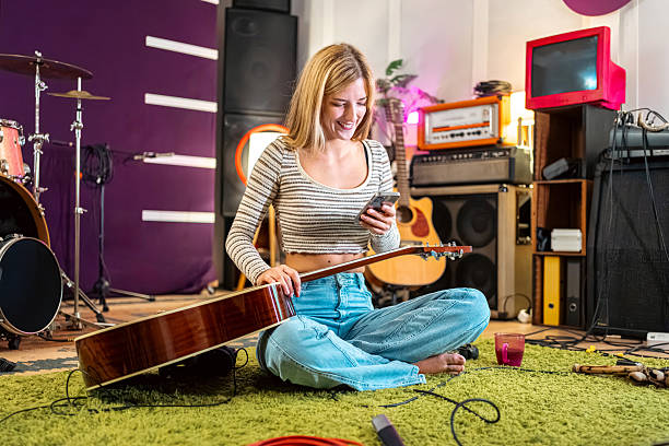 istock Young woman using her smart phone with guitar in lap 2239954624