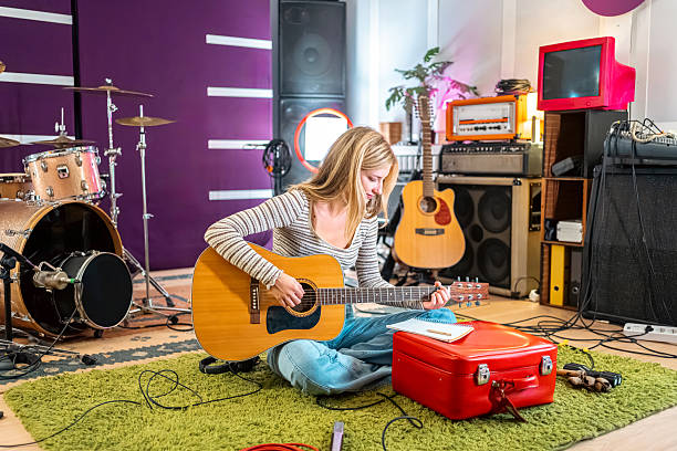 istock Beautiful young woman practicing guitar in a music studio 2239954684