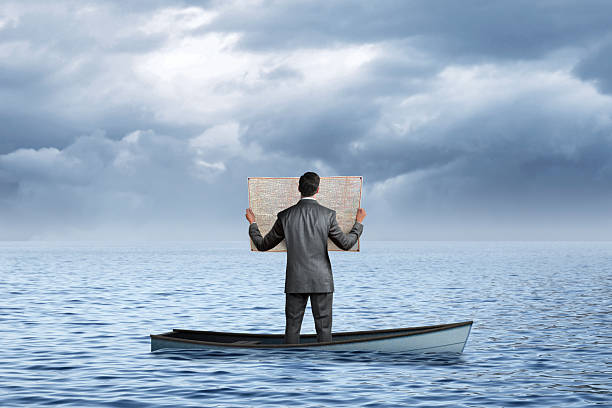 istock Man In Sinking Boat Looks At Road Map 2239957287