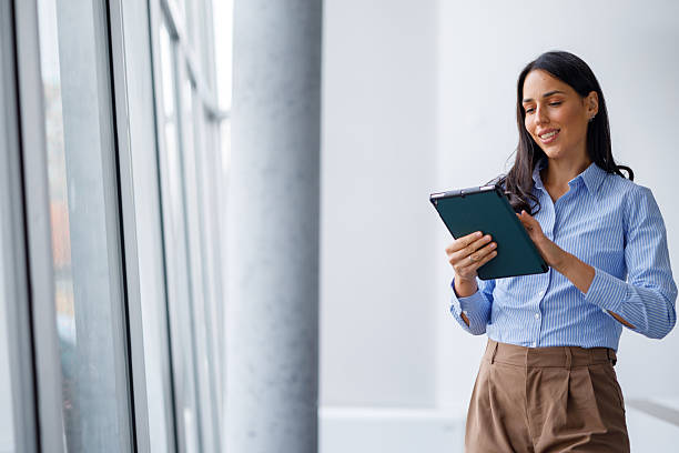 istock Businesswoman standing in modern office using digital tablet for work, smiling and networking 2239961765