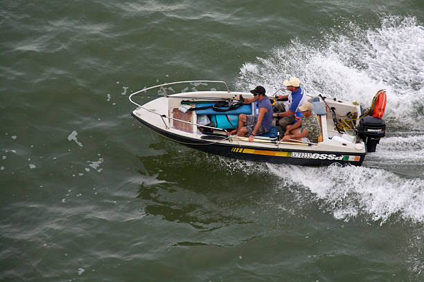 Venice. Italy - October 08, 2025: Three men in a speedboat, on a local fishing excursion, cruise at speed across the Venetian Lagoon.