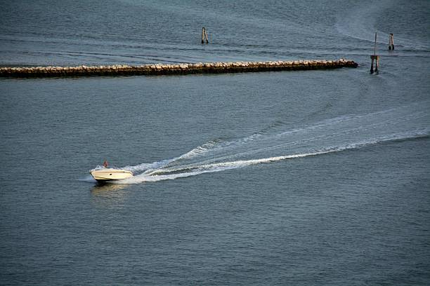 Venecia. Italia - October 08, 2025: A lone speedboat accelerates across open water, leaving a long wake behind as a symbol of speed, progress, and moving forward with purpose.