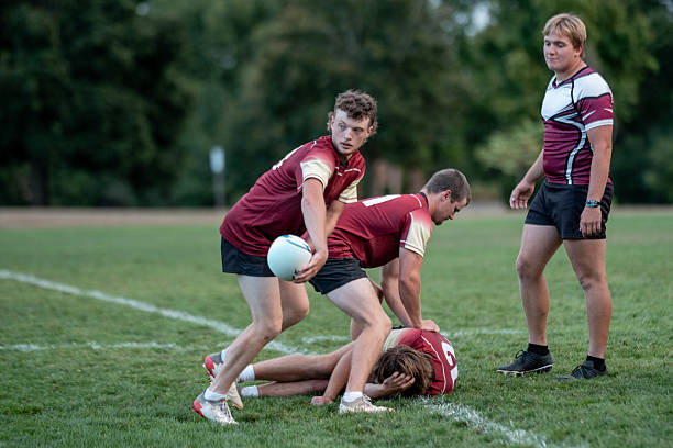 istock Rugby Team Scramble On Grass Field During Match, Teammates Help Fellow Player 2239964312