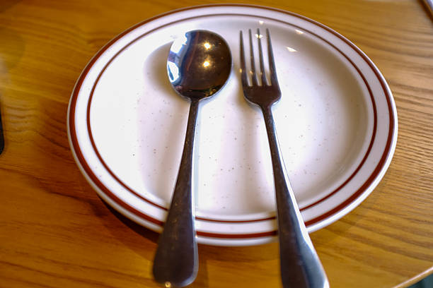 Close up of the cutlery, a spoon and fork on the plate. Table setting for dining. Tableware. Food and utensils concept.