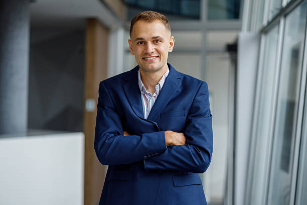 istock Confident and professional young businessman in a modern office setting, posing with crossed arms and a smile for the camera 2239971478