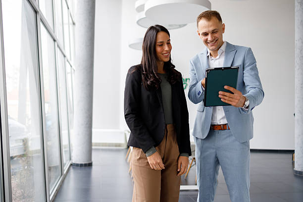 istock Business colleagues collaborating, standing in modern office, having discussion, smiling and using digital tablet 2239971480