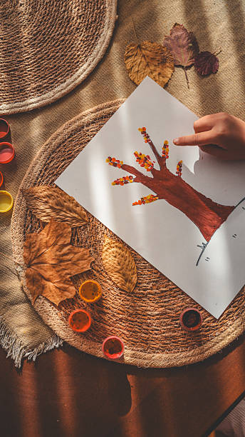 Autumn-themed artwork with a child's hand pointing at a painted tree