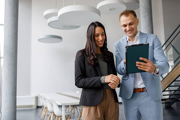 istock Professional colleagues collaborating, smiling, discussing a project on a digital tablet in a modern office setup 2239971632