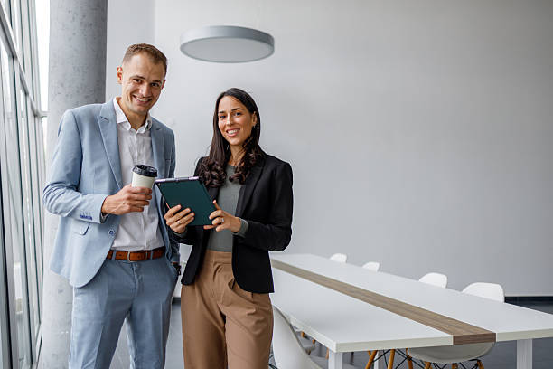 istock Business colleagues collaborating on digital tablet in modern office with coffee cup, standing by meeting table 2239972024