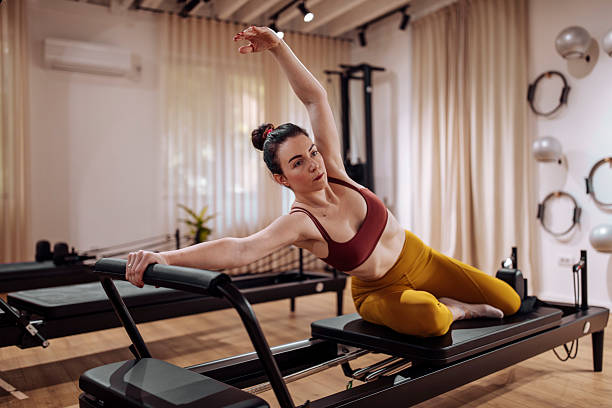 istock Pilates Studio Session: Woman Demonstrates Core Strength and Flexibility on a Reformer Machine 2239972208