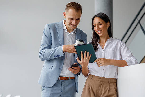 istock Young adult business professionals using a tablet and smiling, discussing work and sharing ideas during a casual pause 2239972481