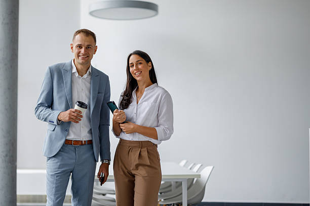 istock Professional colleagues smiling, walking in modern office discussing work during coffee break 2239972623