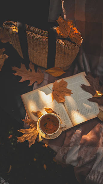 istock Autumn scene with a cup of tea, book, and fall leaves 2239972931