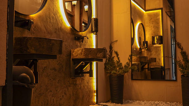 three wall-mounted lights with frosted glass shades emit warm light onto a beige wall.