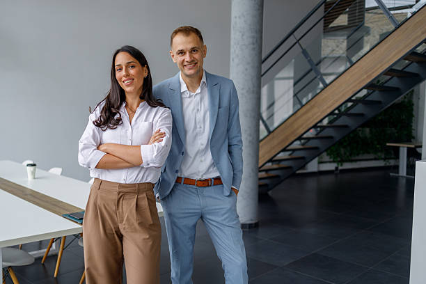 istock Business colleagues standing in modern office, smiling, representing teamwork and professional success 2239974706