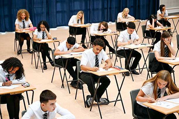 istock Multiracial high school children sitting at desks during exam, boy checking his work 2239976399