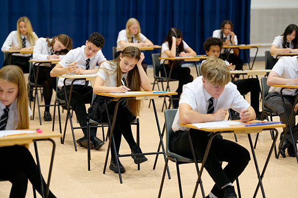 istock Secondary school children sitting at desks and writing in booklets during exam 2239976426