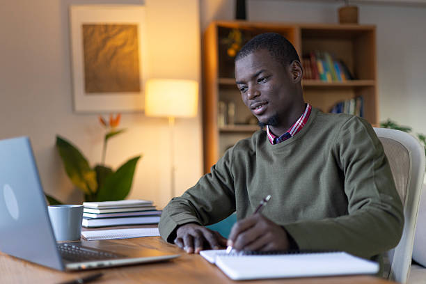istock Young adult student studying at home, writing notes and using a laptop 2239977080