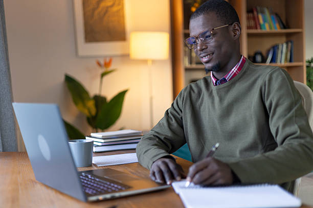 istock Happy young adult man working from home, using laptop and writing in a notebook 2239977083