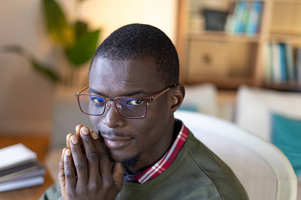 istock Young black man in glasses smiling and looking thoughtful while working from home 2239977123