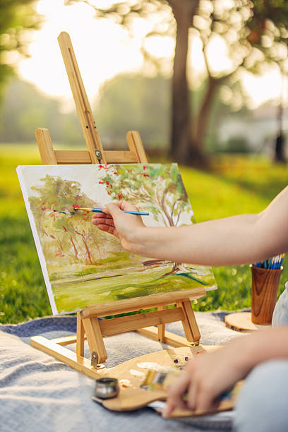 istock Artist painting nature scenery outdoors in a serene park setting 2239977956