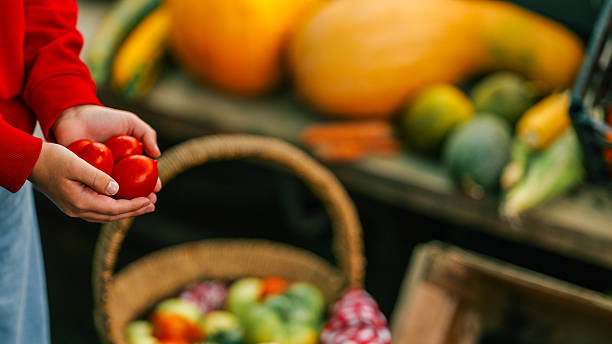 Person holding fresh red tomatoes at a farmers market