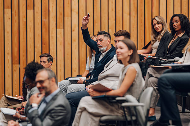 istock Man raising hand asking question at business conference 2239980016