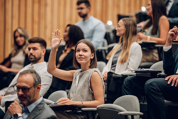 istock Young woman raising hand asking question in conference 2239980689
