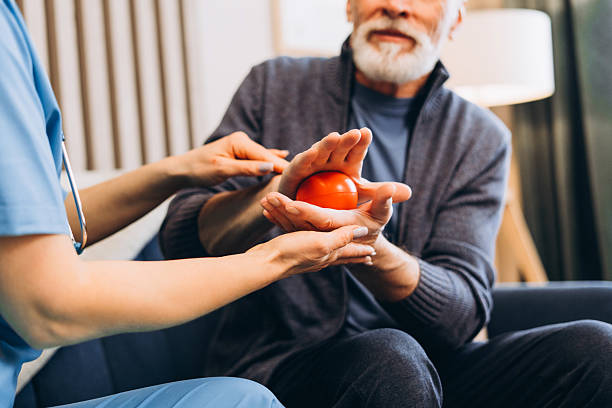 istock Professional nurse assisting senior man with hand therapy exercise selective focus close up 2239990612