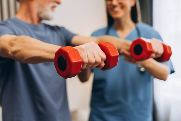 istock Senior man doing rehabilitation exercises with nurse selective focus on hands closeup 2239990616