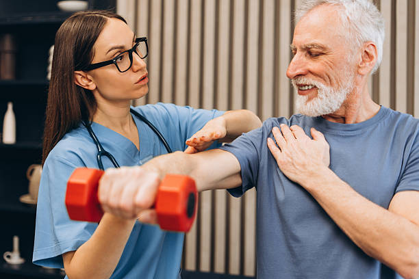 istock Young physical therapist assisting senior man with rehabilitation exercise 2239991142