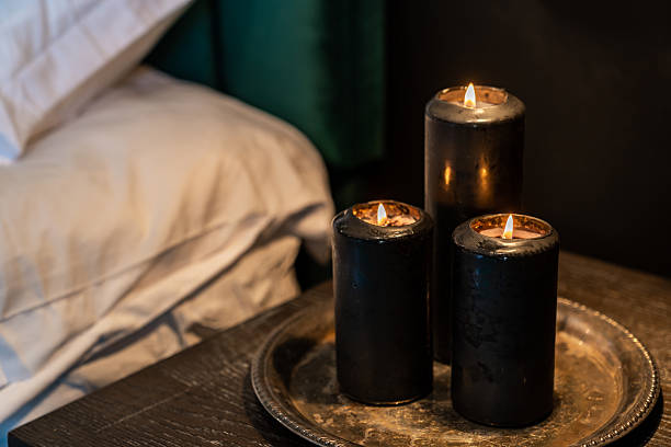 istock Black candles burning flame on silver platter beside bed on nightstand 2239992858