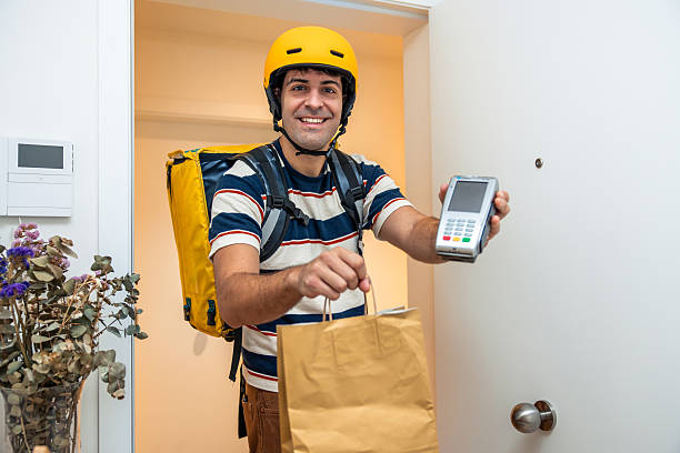 istock Delivery man holding payment terminal and order bag 2239993154