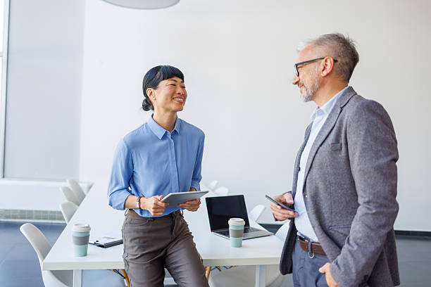 istock Two colleagues talking and working with technology in a bright office 2239995398