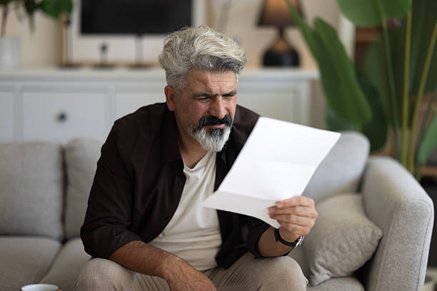 istock Shocked man reading some bills energy expenses on sofa living room 2239995621