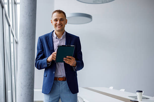 istock Businessman smiling, using a digital tablet in a bright, contemporary office, representing professionalism and success 2239997522