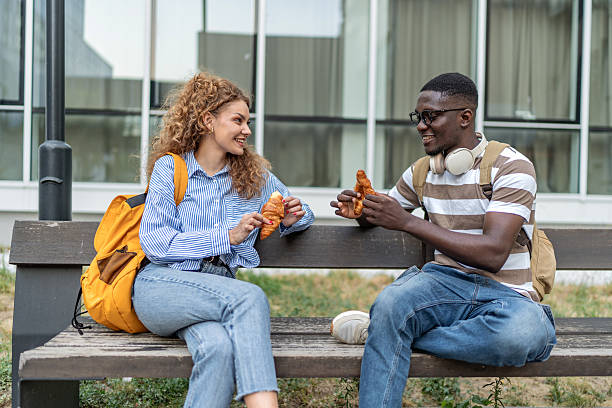 istock Diverse young adults eating croissants and talking on bench 2239998848