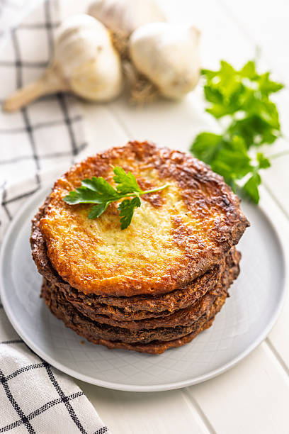 Fried potato pancakes on plate on white table.